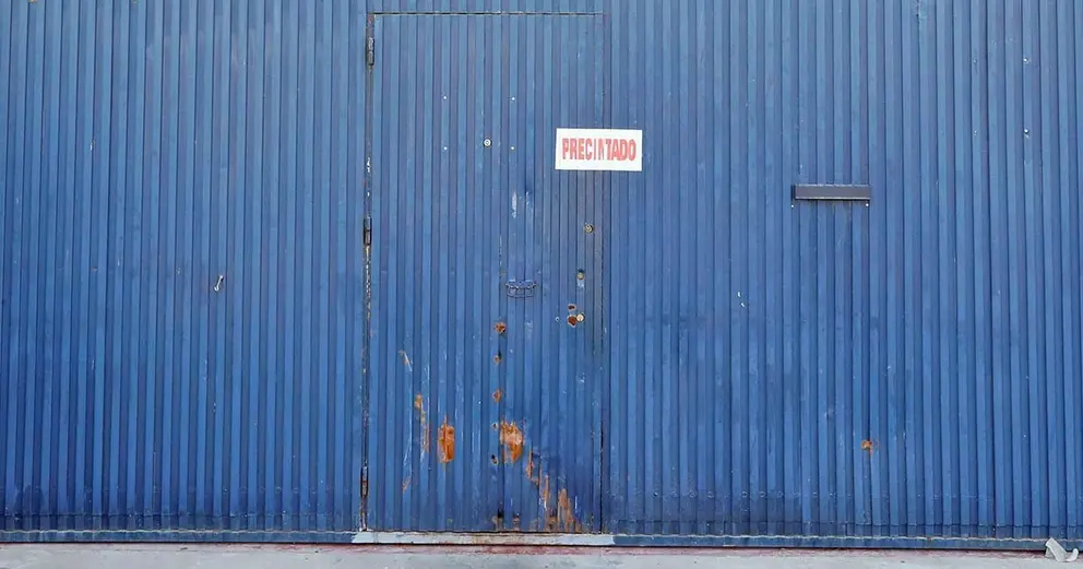 GRAFAND006. SEVILLA, 30/08/2019.- Fachada y puerta de la f&aacute;brica Magrudis, en el Pol&iacute;gono sevillano de El Pino, empresa fabricante de la carne mechada contaminada con listeriosis, que ha sido precintada por el Ayuntamiento de Sevilla al haber formalizado hoy viernes ante la Fiscal&iacute;a una denuncia contra esta factor&iacute;a por un delito contra la salud p&uacute;blica. EFE/Jos&eacute; Manuel Vidal