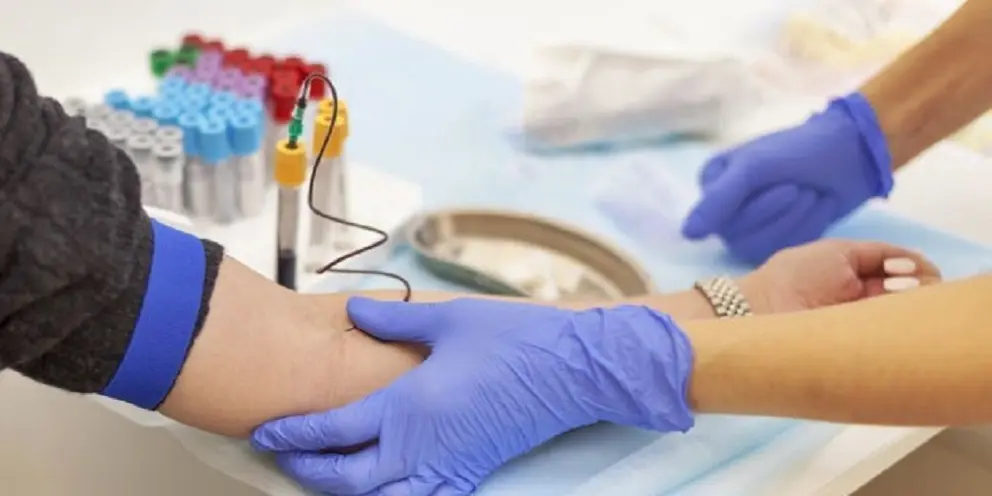 A doctor in blue gloves takes blood from a vein from a young woman. Several test tubes. Diagnosis, disease, examination concept.