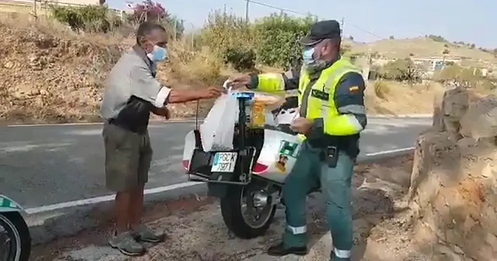 Un guardia civil entrega comida a una persona necesitada.