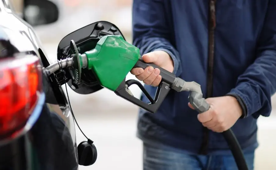 Un hombre echando combustible a su coche 