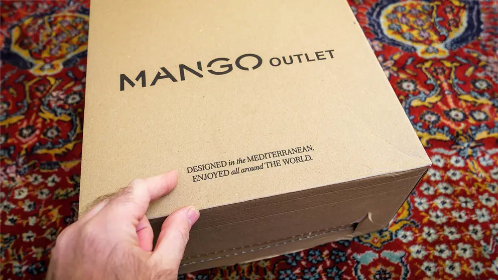 Paris, France - Dec 2, 2022: A hand is pointing to a package of an internet order from the fashion brand Mango Outlet. The detailed cardboard parcel provides a unique view into online e-commerce.