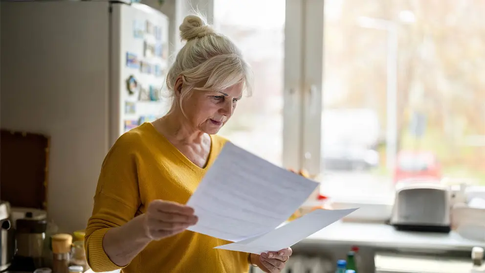 Mujer revisa documentaci&oacute;n en la cocina