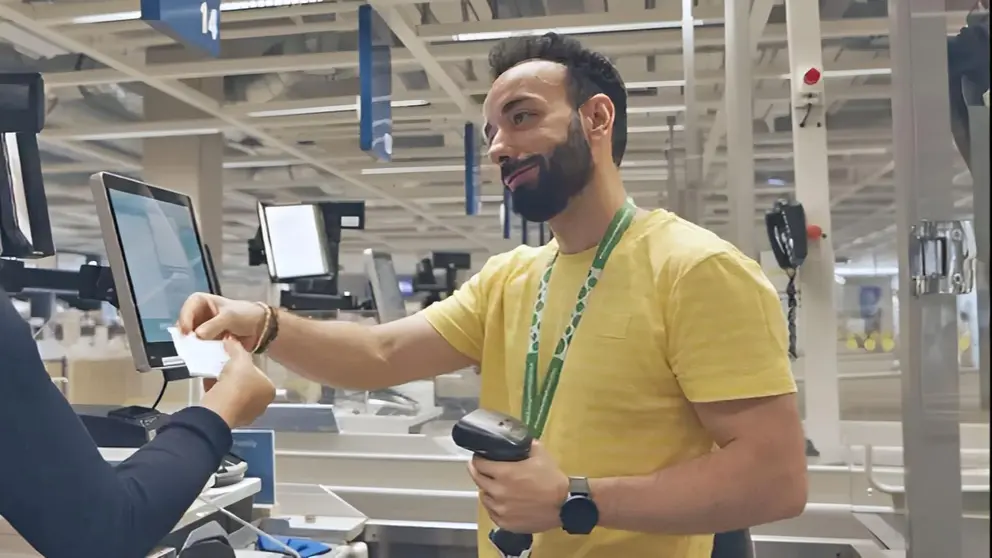 Trabajador de IKEA cobrando a una clienta en la pasarela de pago