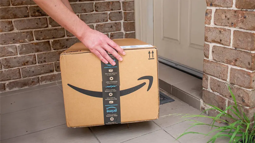 Repartidor deja una caja de Amazon en un domicilio