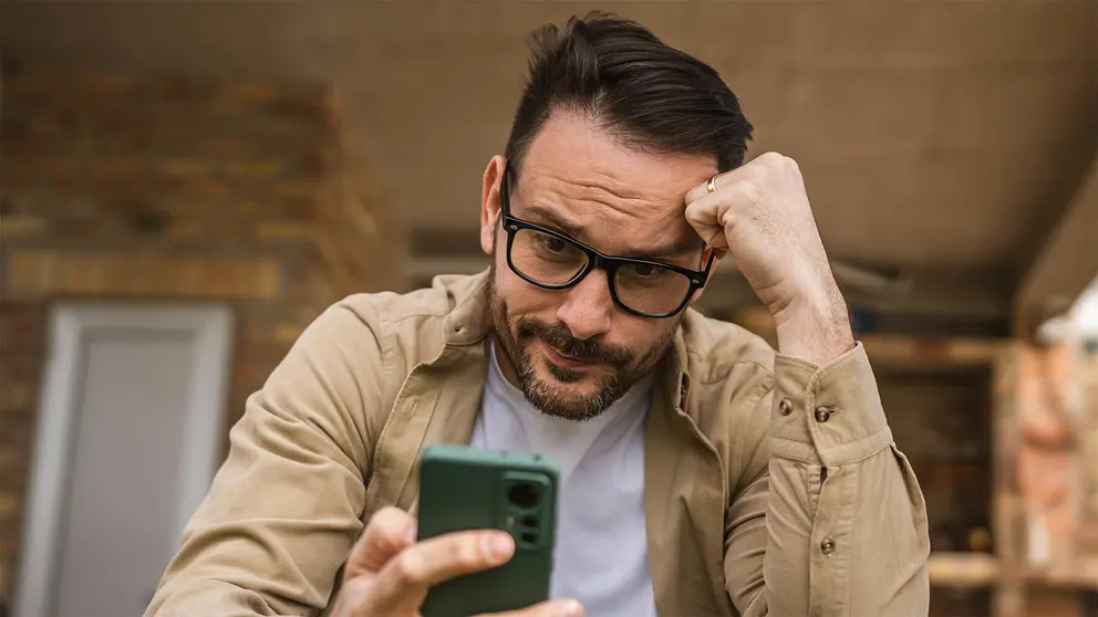 Hombre recibe noticia en su m&oacute;vil en la puerta de su domicilio