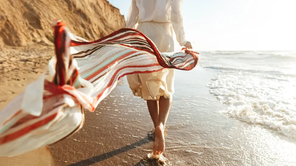 Mujer pasea por la orilla de la playa