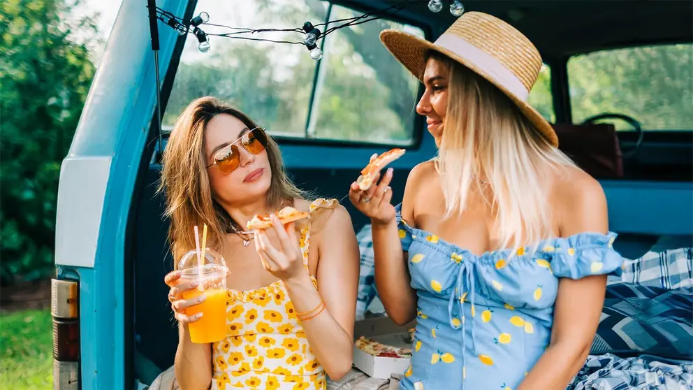 Mujeres almuerzan en el coche y beben bebida refrescante