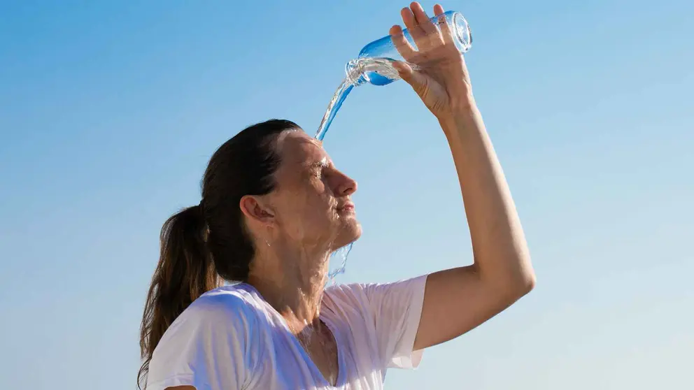 Una mujer con calor tir&aacute;ndose agua por encima