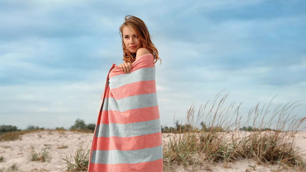 Joven en la playa cubierta por la toalla