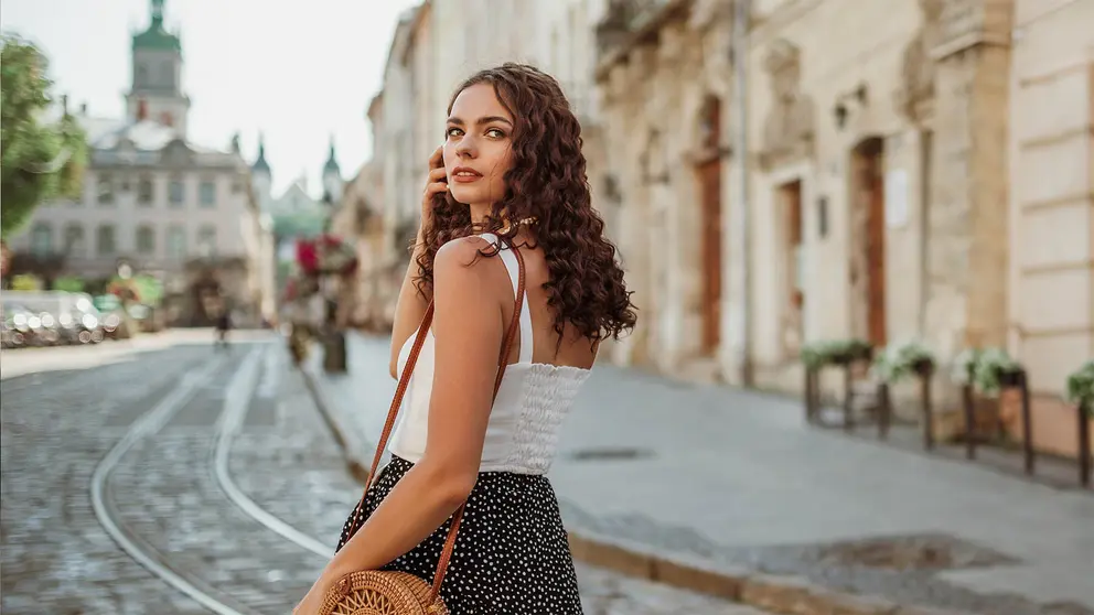 Mujer viste elegante con un bolso por la ciudad