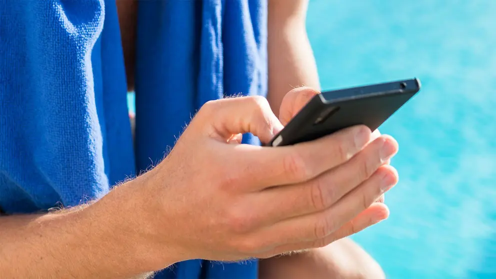 Nadador sostiene el m&oacute;vil al borde de la piscina