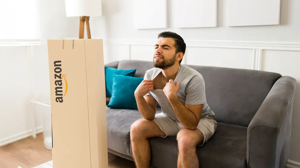 Hombre con calor en el sof&aacute; junto a una caja de Amazon