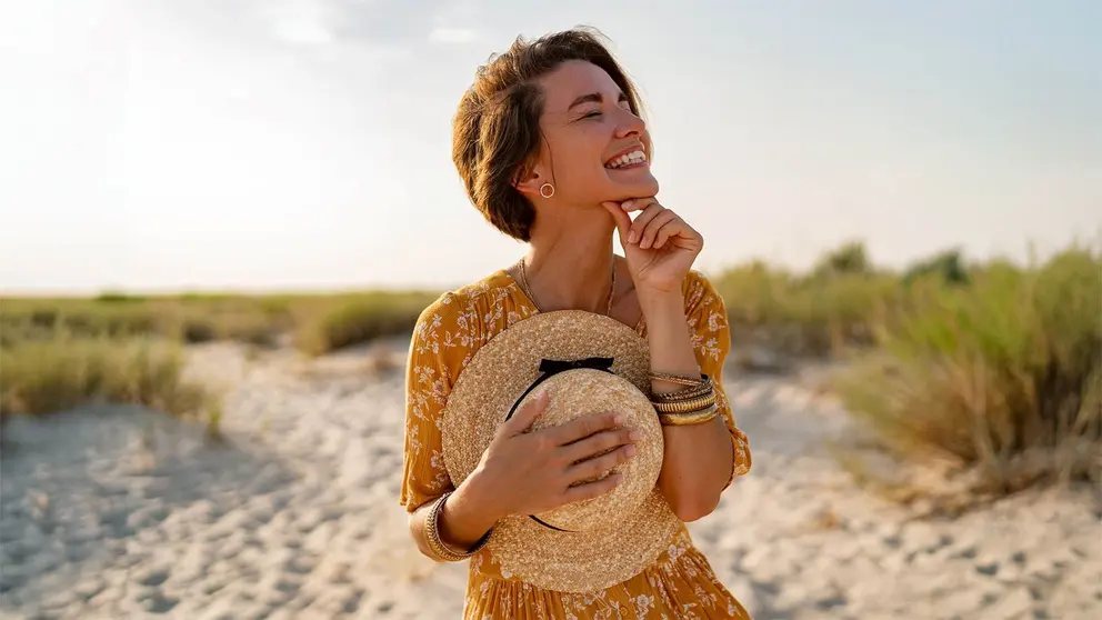 Mujer con vestido sonriente en la playa en verano