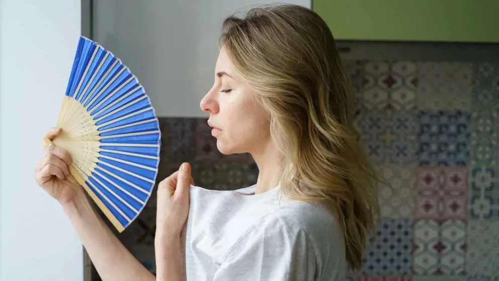 Una mujer con calor abanic&aacute;ndose
