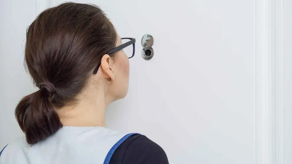 Una mujer mirando por la mirilla de una puerta