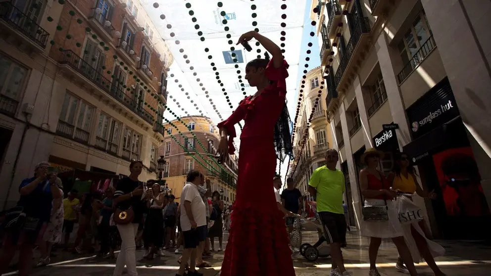 Una mimo vestida con traje de flamenca act&uacute;a en la calle Larios, en la Feria del Centro de M&aacute;laga