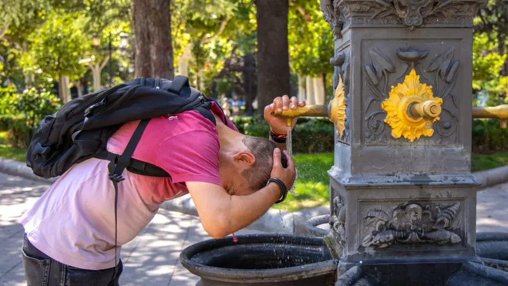 Una persona se refresca con agua de la fuente