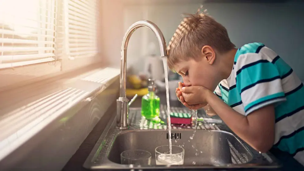 Un ni&ntilde;o bebiendo agua del grifo