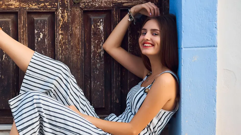 Joven apoyada en el portal de un edificio mostrando sus sandalias