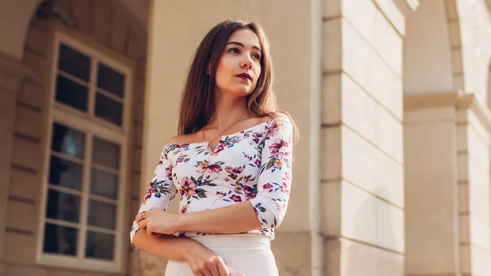 Joven sostiene un bolso mientras espera en una mansi&oacute;n