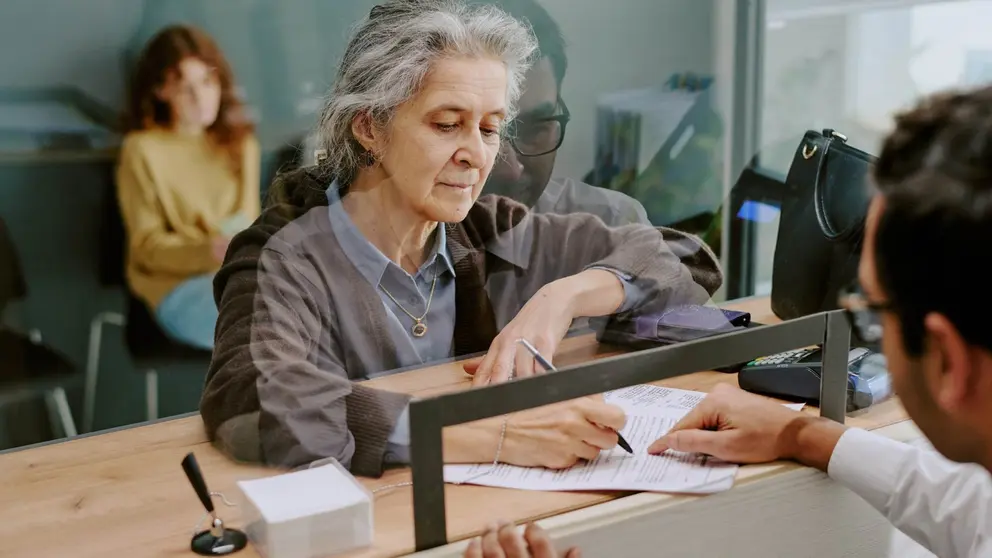 Mujer atendida en la ventanilla de una sucursal bancaria