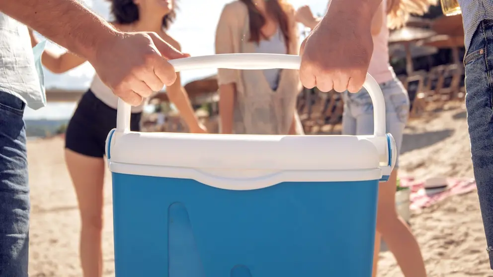 Ba&ntilde;istas cargan juntos en peso la nevera en la playa