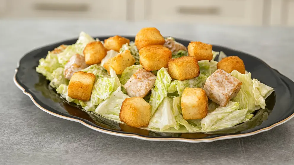Receta r&aacute;pida de ensalada C&eacute;sar con lechuga crujiente y dados de queso