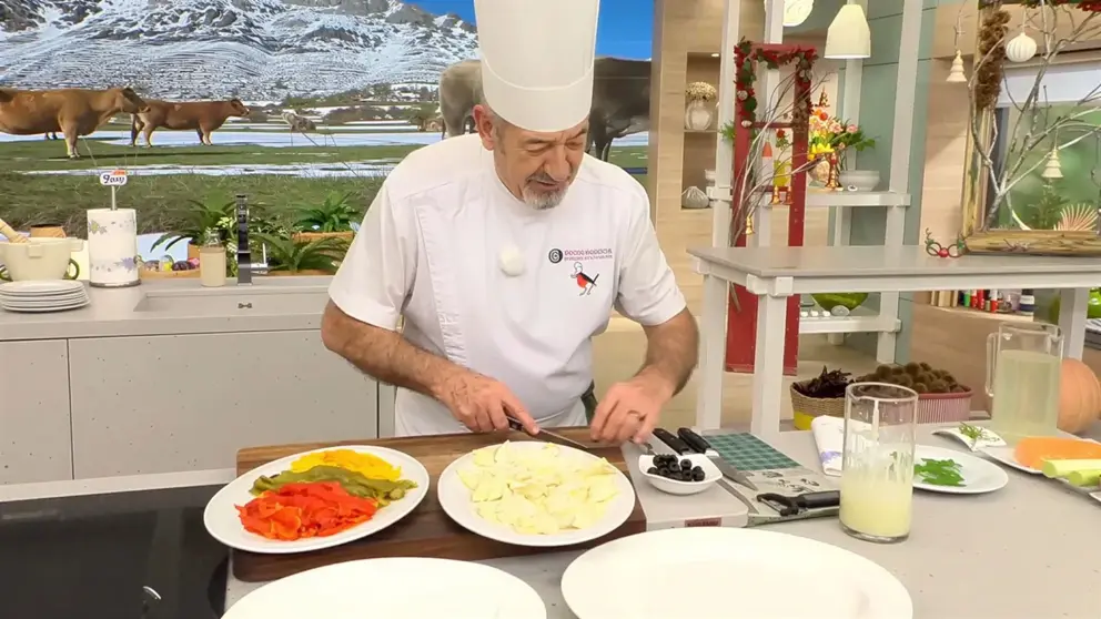 Karlos Argui&ntilde;ano en la cocina elaborando la ensalada de pimientos al horno con bacalao