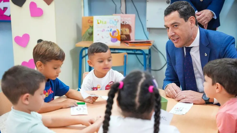 Juanma Moreno, junto a un grupo de ni&ntilde;os en un colegio