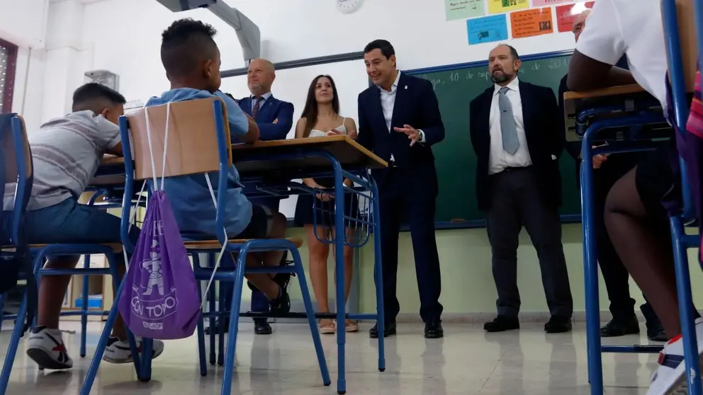 Juanma Moreno conversando con ni&ntilde;os en un colegio