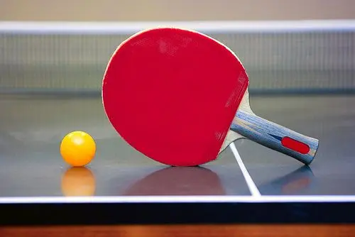 Ping pong ball and racket lying in the corner of the table