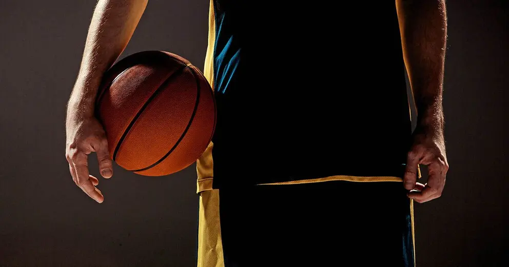 The silhouette view of a basketball player holding basket ball on black background