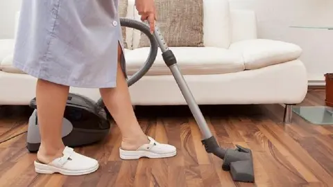Young Maid Cleaning Floor With Handheld Vacuum Cleaner
