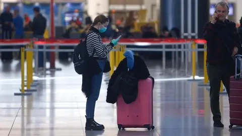 Una turista con mascarilla y guantes en el aeropuerto de M&aacute;laga - &Aacute;LEX ZEA/EUROPA PRESS