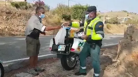 Un guardia civil entrega comida a una persona necesitada.