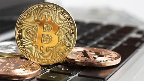 Monedas de Bitcoin en un ordenador port&aacute;til