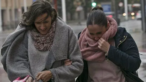 Dos mujeres se protegen del viento