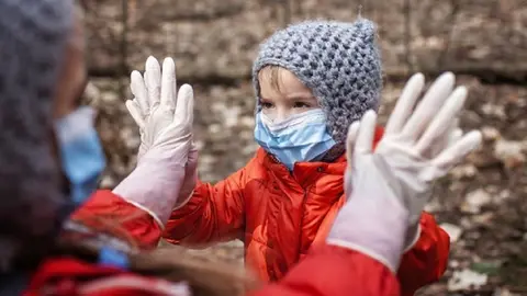 Ni&ntilde;o con mascarilla y abrigado jugando