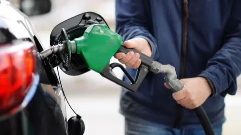 Un hombre echando combustible a su coche 