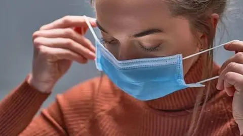 Una mujer coloc&aacute;ndose una mascarilla