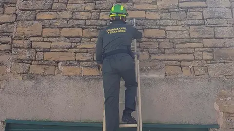 Un agente de los Tedax accede al proyectil incrustado en una fachada de Porcuna