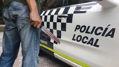 Un hombre con un cuchillo junto a un coche de la Polic&iacute;a Local