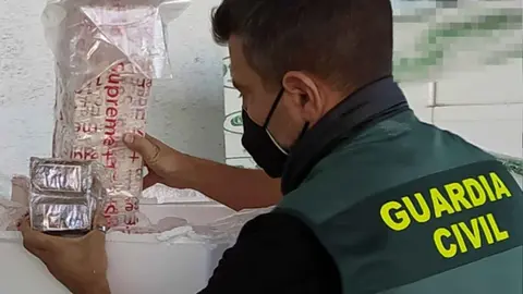 Un agente de la Guardia Civil sacando la droga del palet