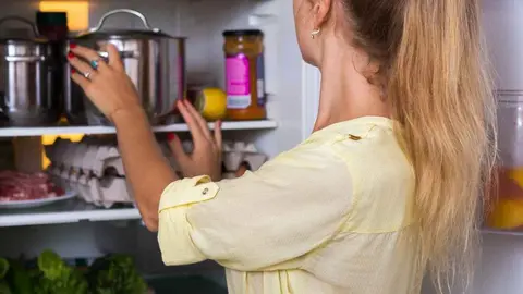 Una joven cogiendo comida de la nevera