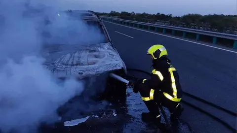 Un bombero apagando el incendio del coche