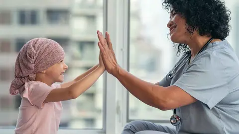 Una ni&ntilde;a con c&aacute;ncer junto a una enfermera