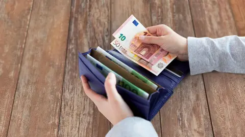 Una mujer guardando dinero en una cartera