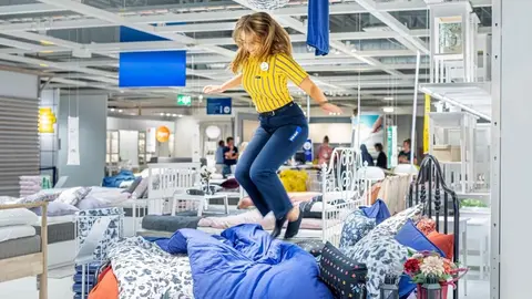 Trabajadora de IKEA salta sobre una cama para demostrar su durabilidad y resistencia