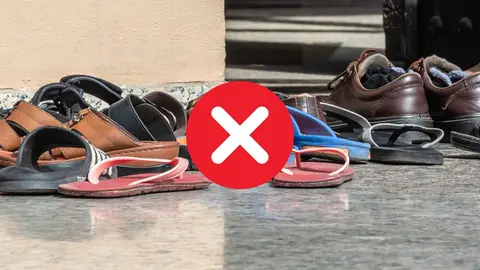 Suelo de una entrada a una casa llena de zapatillas, zapatos, sandalias y chanclas por el suelo