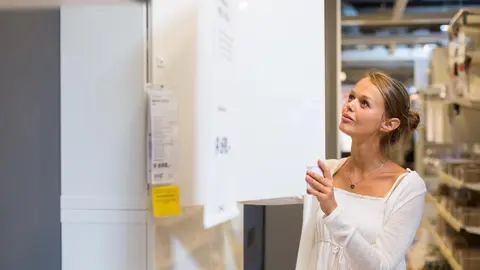 Pretty, young woman choosing the right furniture for her apartment in a modern home furnishings store (color toned image; shallow DOF)